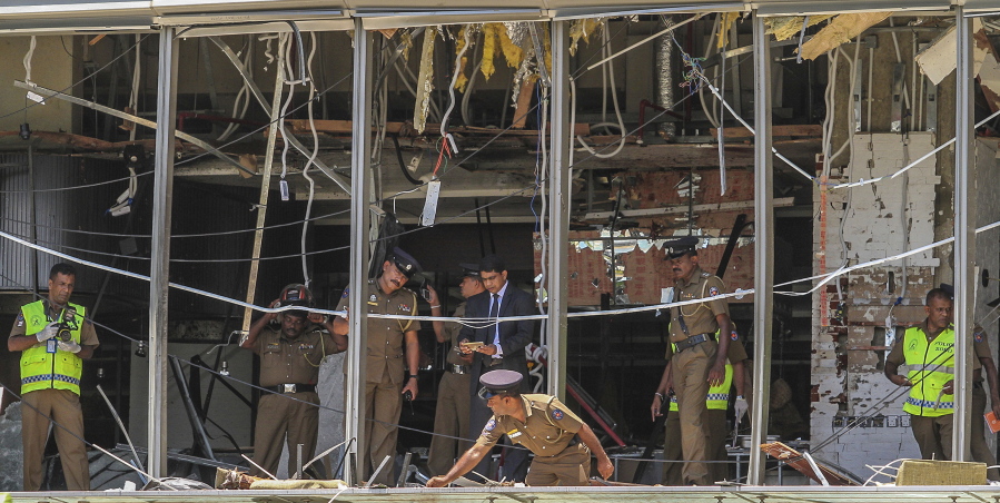FILE- In this Sunday April 21, 2019, file photo, Sri Lankan police officers inspect the site of an explosion at the Shangri-la hotel in Colombo, Sri Lanka. Sri Lanka has filed 23,270 charges against 25 people in connection with the 2019 Easter Sunday suicide bomb attacks on churches and hotels that killed 269 people, the president's office said Wednesday, Aug. 11, 2021.