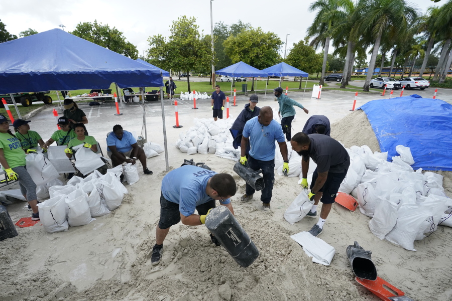 City workers fill sandbags at a drive-thru sandbag distribution event for residents ahead of the arrival of rains associated with tropical depression Fred, Friday, Aug. 13, 2021, at Grapeland Park in Miami. Forecasters say tropical depression Fred is slowly strengthening and could regain tropical storm status Friday.