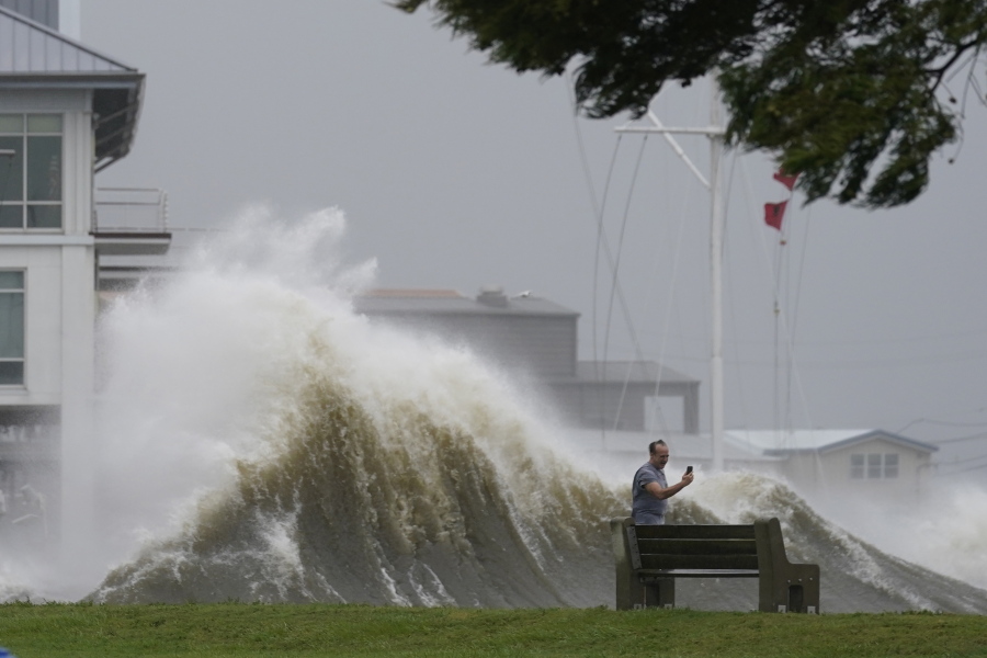 A man takes pictures of high waves along the shore of Lake Pontchartrain as Hurricane Ida nears, Sunday, Aug. 29, 2021, in New Orleans.