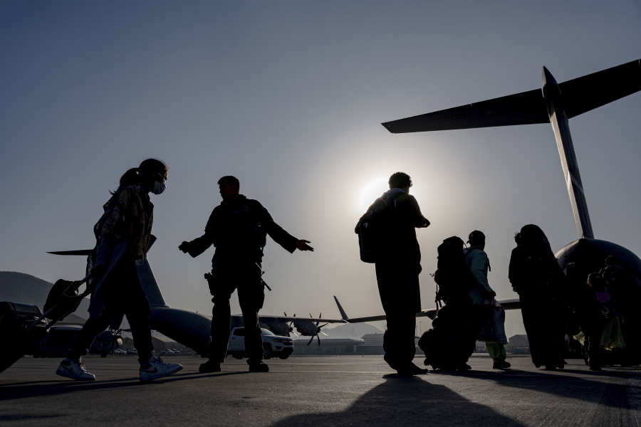 In this image provided by the U.S. Air Force, U.S. Air Force Airmen guides evacuees aboard a U.S. Air Force C-17 Globemaster III at Hamid Karzai International Airport in Kabul, Afghanistan, Tuesday, Aug. 24, 2021. (Senior Airman Taylor Crul/U.S.