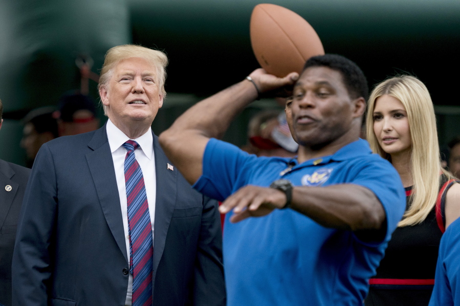FILE - In this May 29, 2018, file photo, President Donald Trump, left, and his daughter Ivanka Trump, right, watch as former football player Herschel Walker, center, throws a football during White House Sports and Fitness Day on the South Lawn of the White House in Washington. On Tuesday, Aug. 17, 2021, Walker filed paperwork to enter the U.S. Senate race in Georgia after months of speculation, joining other Republicans seeking to unseat Democratic Sen. Raphael Warnock in 2022.
