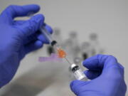 FILE - A pharmacy technician loads a syringe with Pfizer's COVID-19 vaccine, Tuesday, March 2, 2021, at a mass vaccination site at the Portland Expo in Portland, Maine. U.S. experts are expected to recommend COVID-19 vaccine boosters for all Americans, regardless of age, eight months after they received their second dose of the shot, to ensure lasting protection against the coronavirus as the delta variant spreads across the country. An announcement was expected as soon as this week, with doses beginning to be administered widely once the Food and Drug Administration formally approves the vaccines.  (AP Photo/Robert F.