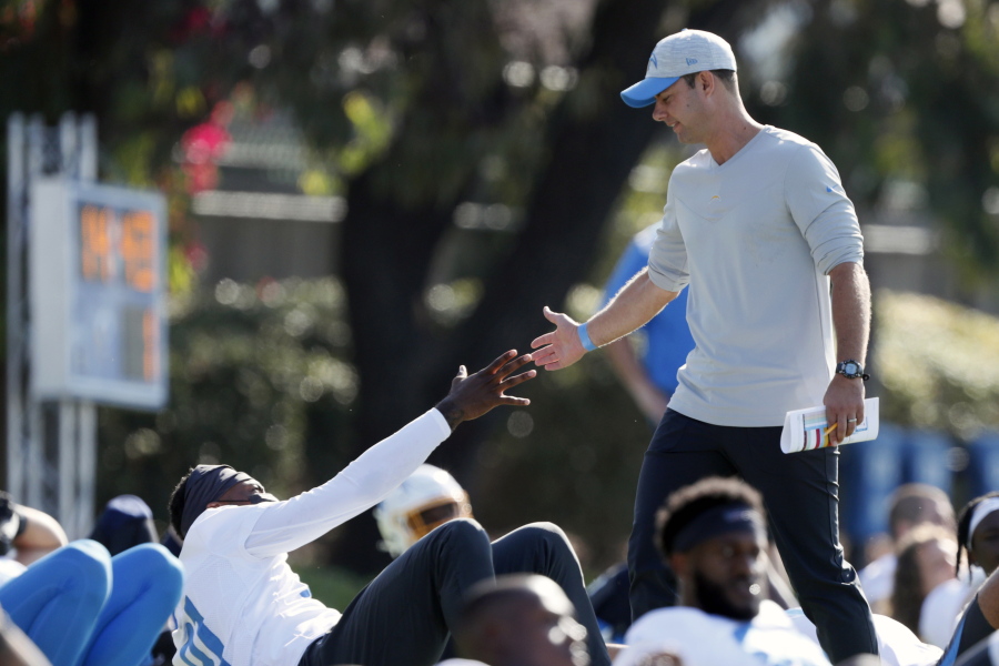 In this July 28, 2021 photo, Los Angeles Chargers head coach Brandon Staley greets wide receiver Mike Williams during practice at the NFL football team's training camp in Costa Mesa, Calif. As workers return to the office, friends reunite and more church services shift from Zoom to in person, this exact question is befuddling growing numbers of people: to shake or not to shake.