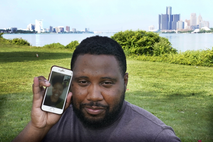 With the cities of Windsor, Canada, left, and Detroit, right, in the background, Quintin Sweat Jr. poses with his fiancee Renee Harrison, seen on his phone, Tuesday on Belle Isle in Detroit.