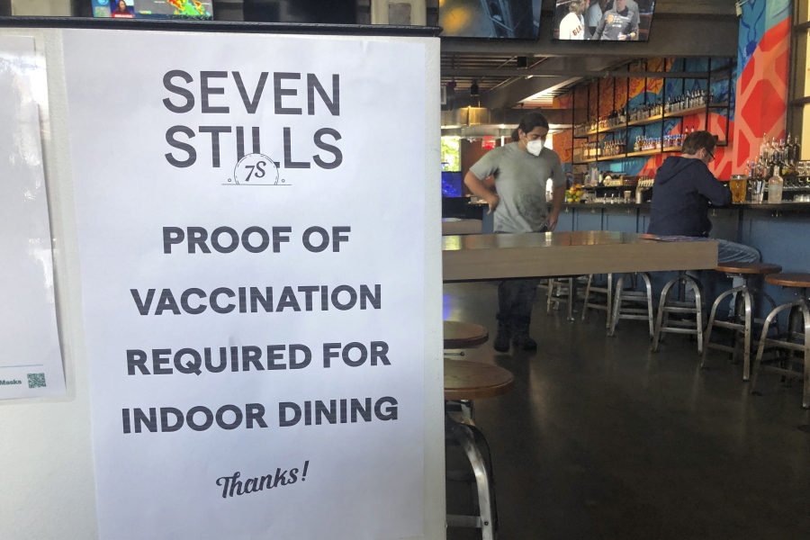 A proof of vaccination sign is posted at a bar in San Francisco on Thursday, July 29, 2021. Until now, many employers had taken a passive approach to their unvaccinated workers, relying outreach and incentives. But that has been shifting, with vaccine mandates gaining momentum.