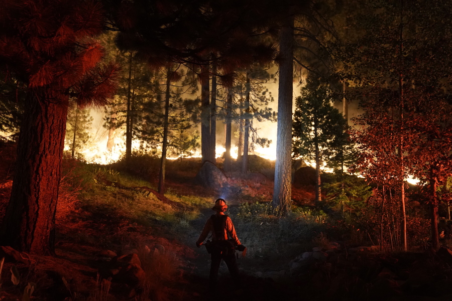 A firefighter monitors the Caldor Fire burning near homes in South Lake Tahoe, Calif., Monday, Aug. 30, 2021. As the winds returned this week, the Caldor Fire roared over the Sierra crest and bore down on the southern end of Lake Tahoe. (AP Photo/Jae C.