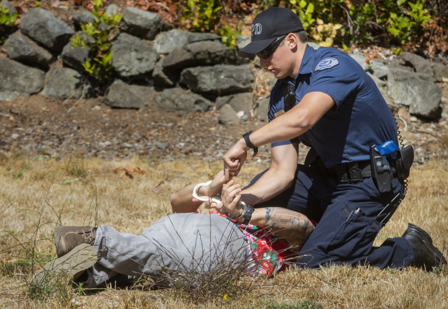 Recruit officer Ryan Rich with the Vancouver Police Department handcuffs "suspect" Don Cornwell,  a recruit with the DuPont Police Department, after a mock fight during an academy class at the Washington Criminal Justice Training Center in Burien, Washington on Wednesday, August 18, 2021, where recruits are learning and using less-than-lethal force alternatives. (Ellen M.