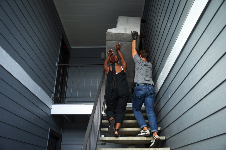 Haley Cummins, housing coordinator, left, and Elijah Knepper, gift-in-kind coordinator for local nonprofit World Relief, heave a large donated sofa up the stairs into a new apartment for a family recently resettled from Kenya to South King County. Housing affordability is a major limiting factor for new refugees arriving to the Seattle area, as well as finding scarce 3-4 bedroom apartments for large families.