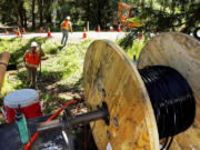 In this May 22, 2018 photo, a Whidbey Telecom crew prepares to thread fiber-optic cable under a road, which will deliver internet service to, in this case, a single home on Whidbey Island, in Freeland, Wash.