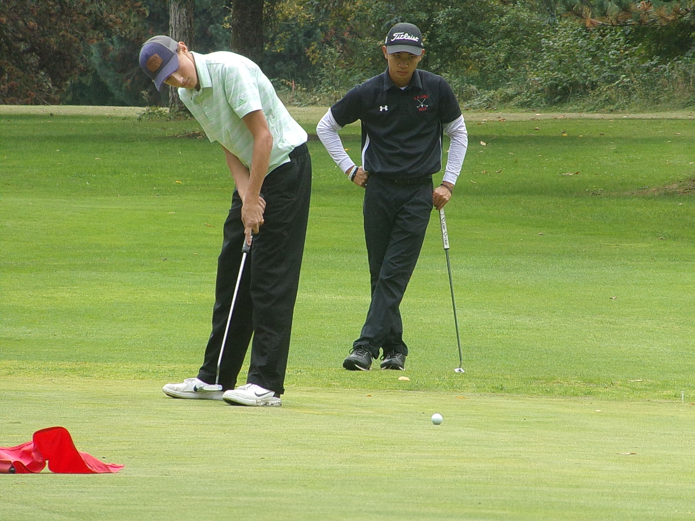 Woodland's Dane Huddleston putts out on No. 18 at Lewis River to win the Prairie Invitational as R.A. Long's Hewie Nguyen watches on Wednesday, Sept.