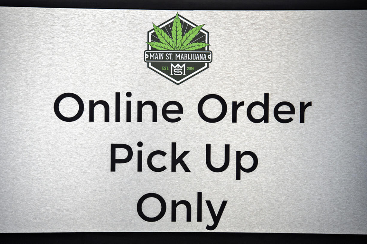 A sign inside Main Street Marijuana directs customers where to pick up their online orders on Aug. 24. Cannabis retailers had to suspend curbside and walk-up service last month, but the state Liquor and Cannabis Board announced Thursday that it would reinstate the allowances for another two months.
