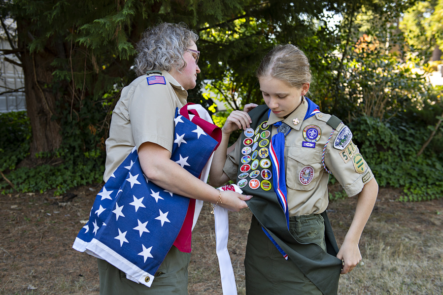 Helene Abbott, left, helps her daughter, Josephine Abbott, 14, as she prepares for a portrait at her home. Josephine has become the first female Eagle Scout in Southwest Washington.