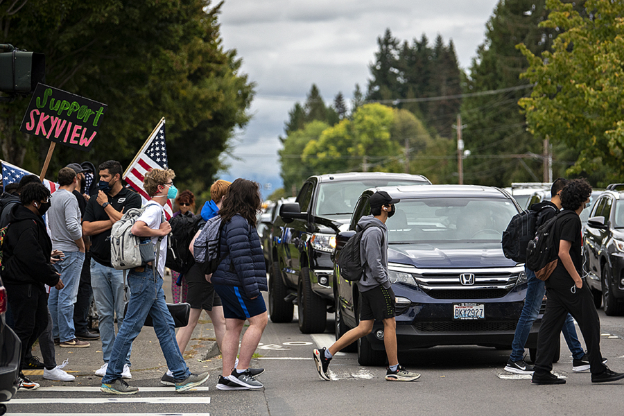 Skyview High School students pass dueling protests outside their school Friday afternoon. Opposing groups expressed different points of view on the Vancouver Public School's injunction prohibiting protests, rallies or other demonstrations that "disrupt educational services" within a mile of Vancouver schools.