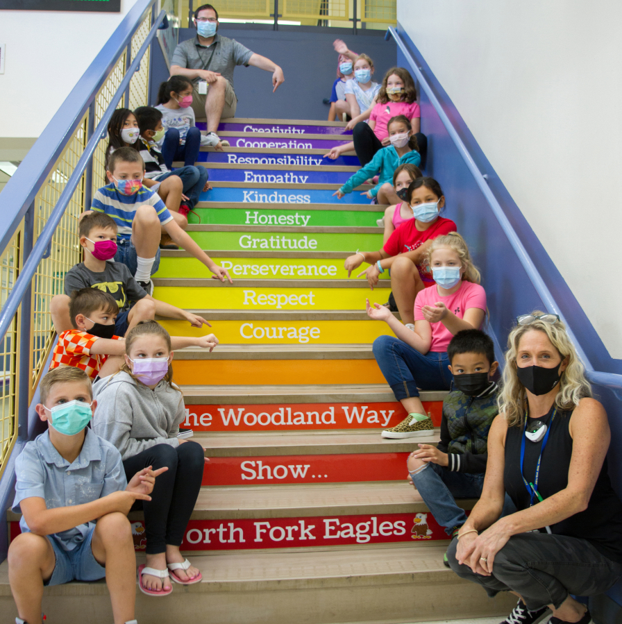 Leadership/SEL teacher Stacia Aschoff, far right, sits with her leadership class on the stairs of North Fork Elementary School in Woodland.