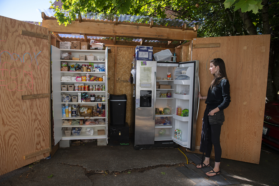 Gretta Anderson looks over contents of the free food pantry and fridge at her Vancouver home Monday afternoon. The Vancouver Free Fridge project is up to three fridges, but they're also being regulated by city codes over the structures, causing program leaders to start a petition.