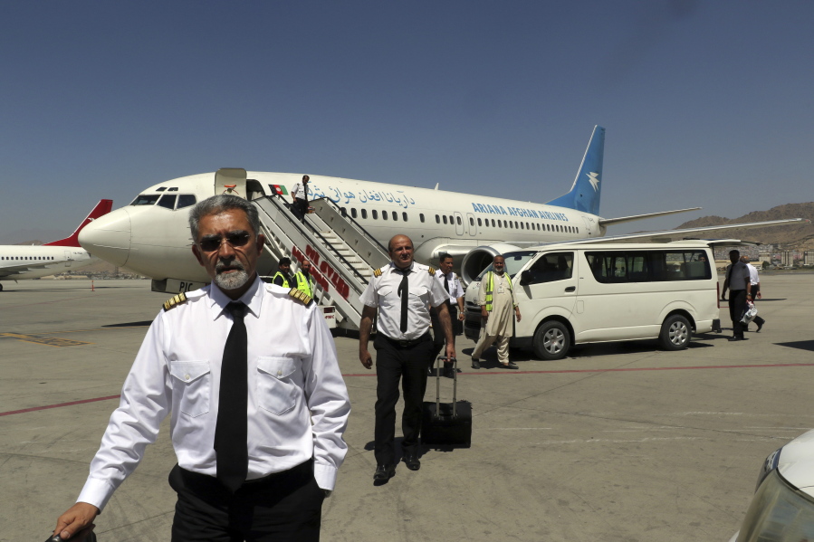 Pilots of Ariana Afghan Airlines walk on the tarmac after landing at Hamid Karzai International Airport in Kabul, Afghanistan, Sunday, Sept. 5, 2021. Some domestic flights have resumed at Kabul's airport, with the state-run Ariana Afghan Airlines operating flights to three provinces.