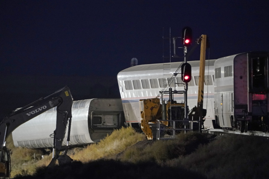 Cars from an Amtrak train that derailed the day before are shown illuminated by floodlights, late Sunday, Sept. 26, 2021, as they rest near a train signal near Joplin, Mont. The westbound Empire Builder was en route to Seattle from Chicago with two locomotives and 10 cars. (AP Photo/Ted S.