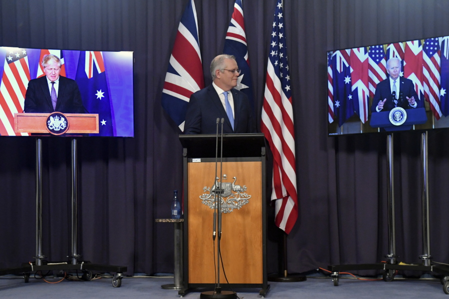 Australia's Prime Minister Scott Morrison, center, appears on stage with video links to Britain's Prime Minister Boris Johnson, left, and U.S. President Joe Biden at a joint press conference at Parliament House in Canberra, Thursday, Sept. 16, 2021. The leaders are announcing a security alliance that will allow for greater sharing of defense capabilities -- including helping equip Australia with nuclear-powered submarines.