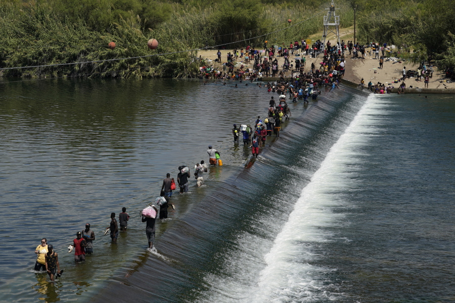 FILE - In this Sept. 18, 2021, file photo Haitian migrants use a dam to cross into the United States from Mexico in Del Rio, Texas. President Joe Biden embraced major progressive policy goals on immigration after he won the Democratic nomination, and he has begun enacting some. But his administration has been forced to confront unusually high numbers of migrants trying to enter the country along the U.S.-Mexico border and the federal response has inflamed both critics and allies.