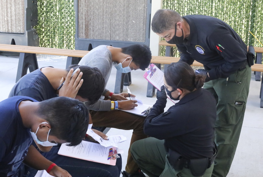 This May 4, 2021, photo provided by The U.S. Border Patrol shows U.S. Border Patrol Processing Coordinators assisting in the processing of underage migrant children at the entrance of the Central Processing Center in El Paso, Texas. The Border Patrol says agents spend about 40% of their time on custody care and administrative tasks that are unrelated to border security, creating a staffing challenge. (U.S.