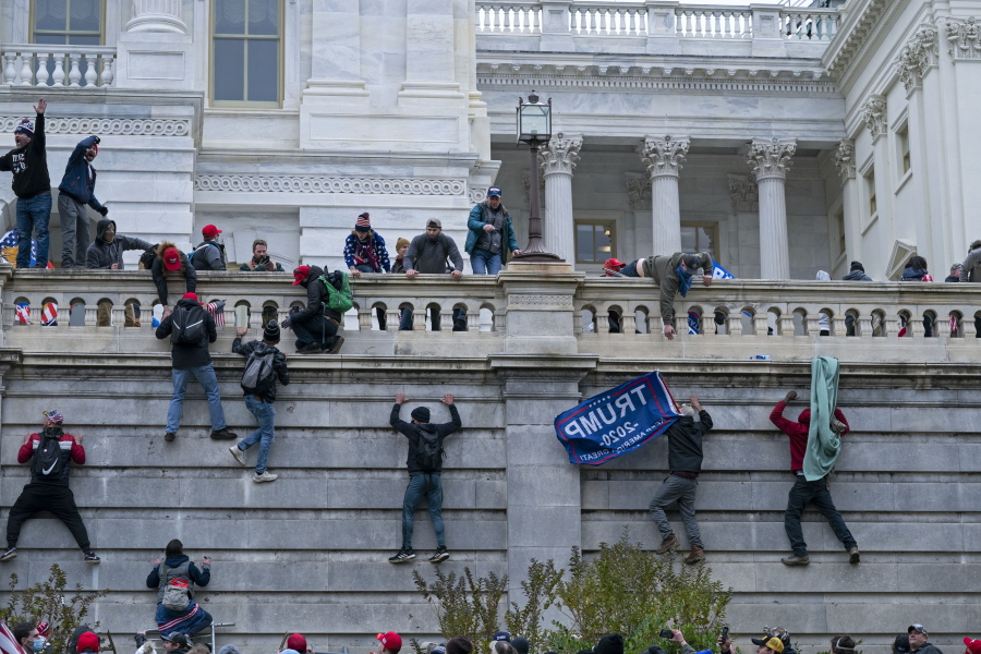 FILE - In this Jan. 6, 2021 file photo, rioters climb the west wall of the the U.S. Capitol in Washington. First, some blamed the deadly Jan. 6 attack on the Capitol on left-wing Antifa antagonists, a theory quickly debunked. Then came comparisons of the rioters as peaceful protesters, or even "tourists." Now, Trump allies rallying in support of those people charged in the Capitol riot are calling them "political prisoners," a stunning effort to revise the narrative of that deadly day.