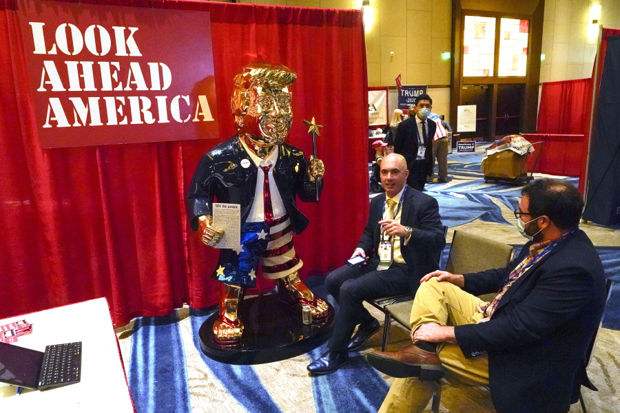 FILE - In this Feb. 26, 2021, file photo, Look Ahead America sponsor Matt Braynard, center, talks to conference attendees at his booth in the merchandise show with a statue of former president Donald Trump at the Conservative Political Action Conference (CPAC) in Orlando, Fla.