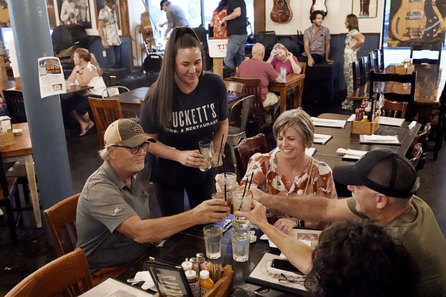 Macy Norman, center, serves a table of guests at Puckett's Grocery and Restaurant, Friday, Sept. 10, 2021, in Nashville, Tenn. In Nashville, tourism has come back faster than downtown office workers following COVID. Nashville's reputation as a tourist destination is buoying restaurants while businesses in other downtown areas have had to adapt as offices remained closed and workers stay home.