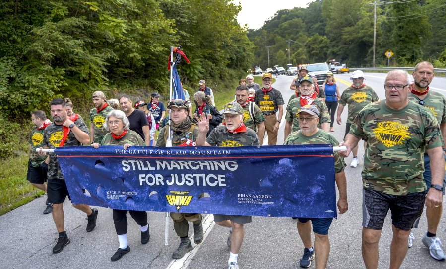 UMWA International President Cecil Roberts, center, with hand raised, leads a chant at the beginning of the march to Blair Mountain on Rt. 94, Friday, Sept., 3, 2021, in Marmet, W.Va. Fed up with poor wages, work and living conditions, thousands of coal miners a century ago marched in an effort to unionize in West Virginia, resulting in a deadly clash and the largest U.S. armed uprising since the Civil War.  On Friday, some descendants of those involved joined others in retracing the steps that culminated in the 12-day Battle of Blair Mountain.
