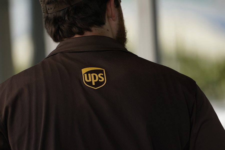 A UPS logo is on the shirt of a driver as he enters a United Parcel Service store with packages in Jackson, Miss., Monday, July 26, 2021.   Amazon, Chobani, UPS and more than 30 other companies have vowed to hire and train refugees fleeing Afghanistan for the U.S. The companies said Tuesday, Sept. 21,  that they want to help the tens of thousands of Afghan refugees coming to America to integrate into the economy.   (AP Photo/Rogelio V.