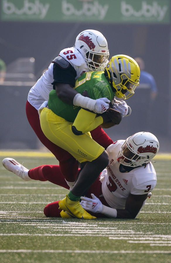 Oregon quarterback Anthony Brown (13) is wrapped up by Fresno State tackle Leonard Payne (55) and defensive end Aaron Mosby (3) during the first quarter of an NCAA college football game, Saturday, Sept. 4, 2021, in Eugene, Ore.
