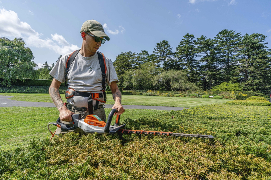 Tyler Campbell uses an electric hedgetrimmer to trim hedges at the New York Botanical Garden in the Bronx borough of New York.