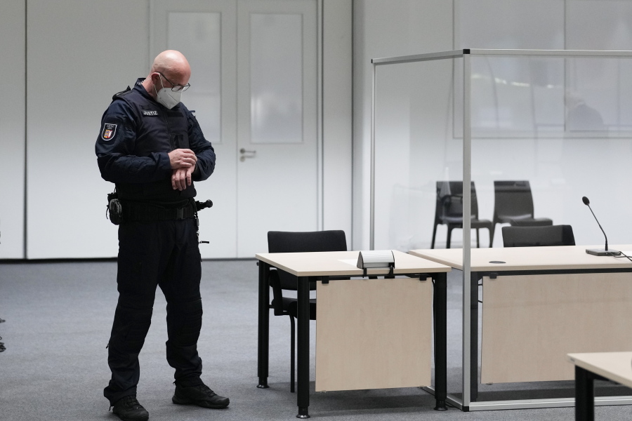A judicial officer looks at his watch prior to a trail against a 96-year-old former secretary for the SS commander of the Stutthof concentration camp at the court room in Itzehoe, Germany, Thursday, Sept. 30, 2021. The woman who is charged of more than 11,000 counts of accessory to murder has not appeared and is wanted by warrant.