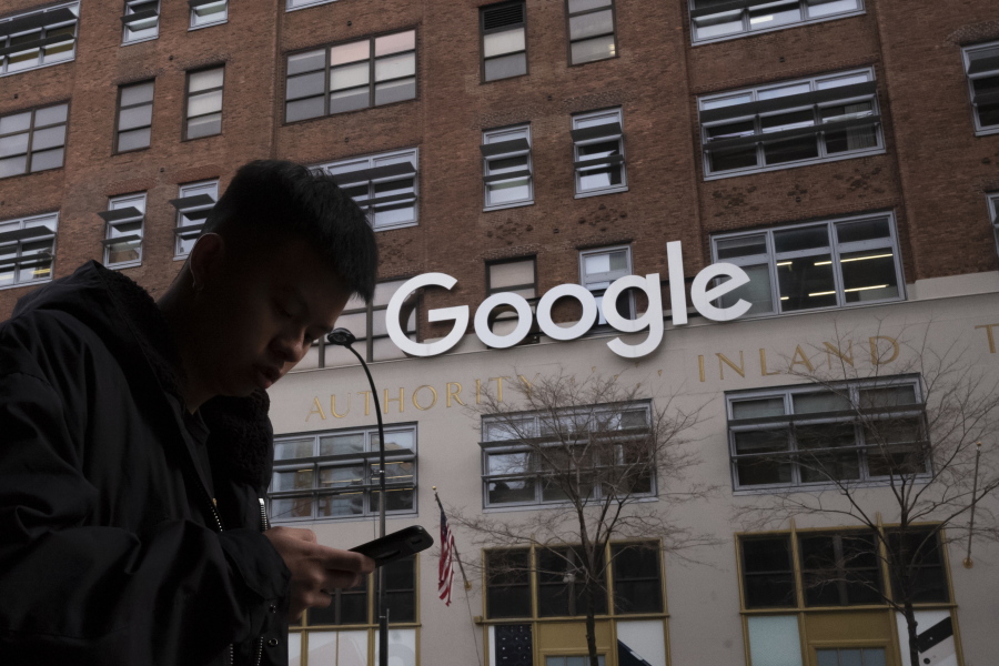 FILE - In this file photo dated Monday, Dec. 17, 2018, a man using a mobile phone walks past Google offices in New York. Google is planning to buy New York's St.  John's Terminal for $2.1 billion, making it the anchor of its Hudson Square campus.
