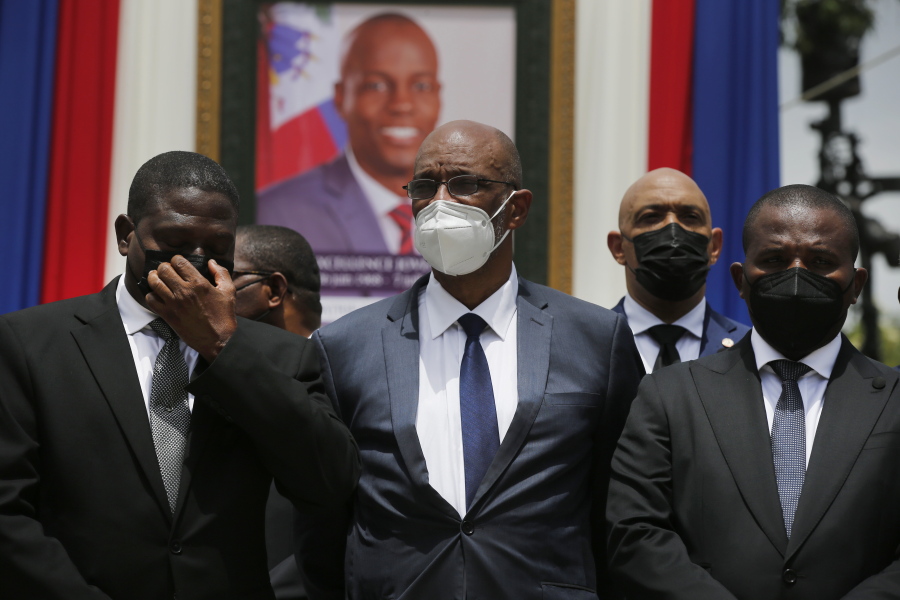 FILE - In this July 20, 2021 file photo, Haiti's designated Prime Minister Ariel Henry, center, and interim Prime Minister Claude Joseph, right, pose for a group photo with other authorities in front of a portrait of slain Haitian President Jovenel Moise at the National Pantheon Museum during a memorial service for Moise in Port-au-Prince, Haiti. Haiti's chief prosecutor has asked a judge to charge Henry in the slaying of his predecessor and barred him from leaving the country.