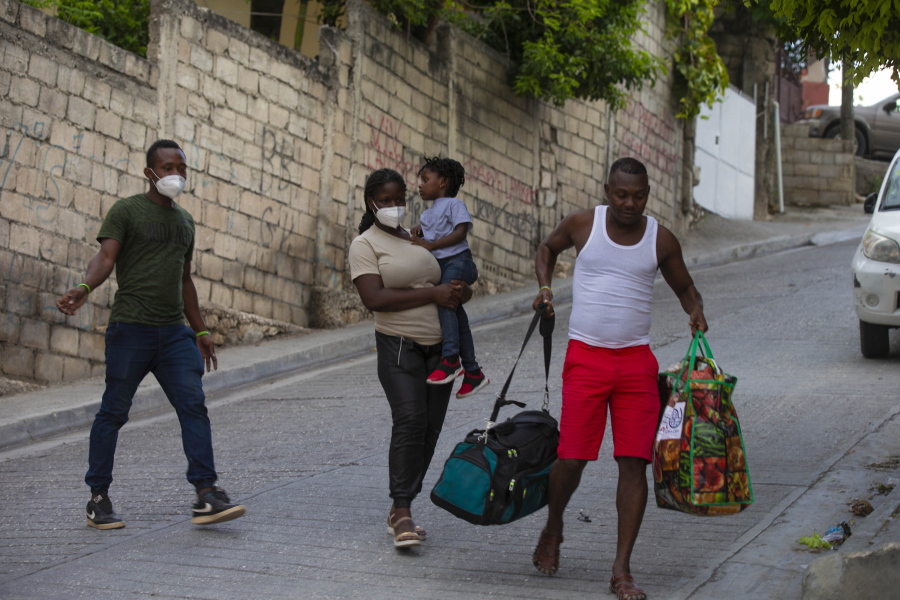 Jean Charles Celestin, right, carries luggage belonging to his cousin Jhon Celestin, left, Jhon's wife Delta De Leon, and their daughter Chloe, in Port au Prince, Haiti, Wednesday, Sept. 22, 2021. Jhon Celestin arrived in Haiti aboard the last flight Wednesday to the Haitian capital, a city the 38-year-old left three years ago in search of a better-paying job to help support his family.