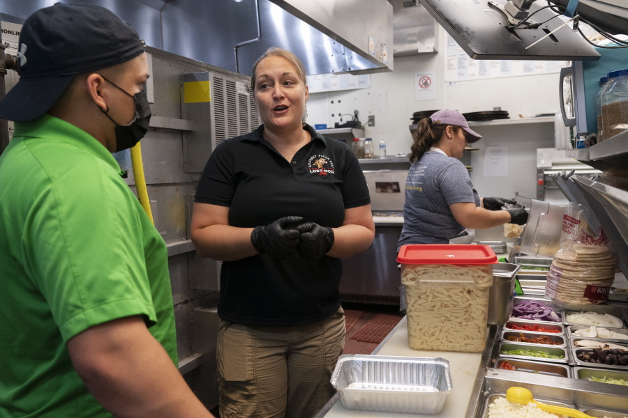 Sarah White, center, area manager of Lost Dog Cafe, trains manager Alex Aleman, left, in a new pasta preparation technique, as they work Aug. 27 at the cafe in Fairfax, Va.