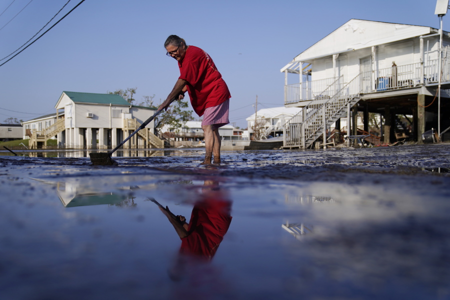 Cindy Rojas cleans mud and floodwater from her driveway in the aftermath of Hurricane Ida, Sunday, Sept. 5, 2021, in Lafitte, La.