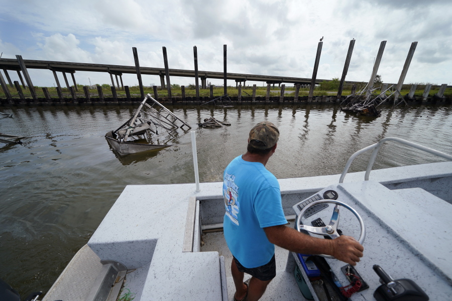 Frank Jurisich motors past shrimp boats that caught fire and burned during Hurricane Ida, as he and his brother go check on their oyster beds Sept. 13 in Plaquemines Parish, La. Ida's heavy rains caused freshwater and sediment to flood coastal estuaries, killing the shellfish, Jurisich said.