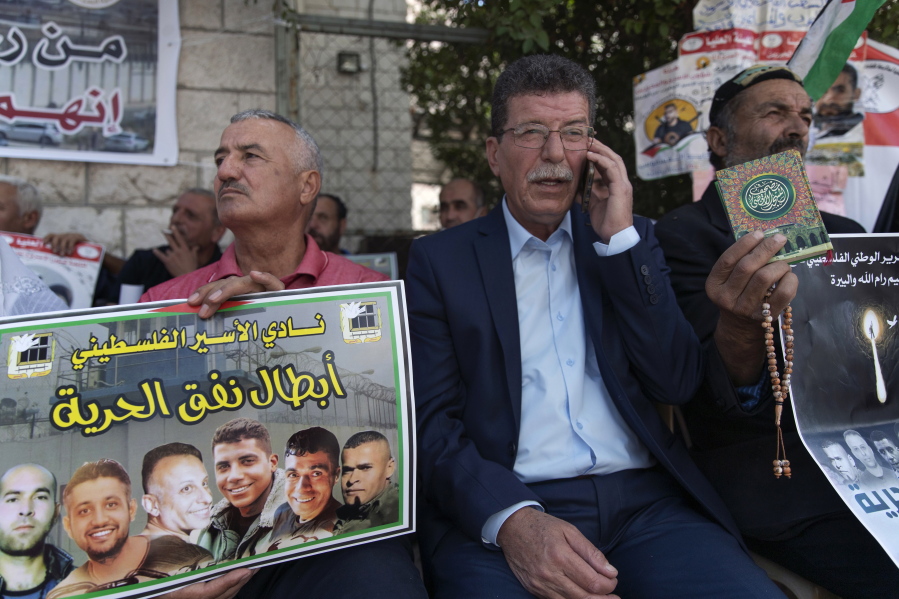 Qadoura Fares, center, attends a protest supporting prisoners, while a fellow protester carries a poster with pictures of the six Palestinian prisoners who escaped from an Israeli jail that says "heroes of the freedom tunnel," in the West Bank city of Ramallah, Tuesday, Sept. 14, 2021.