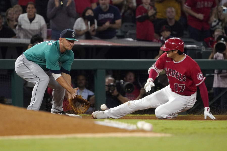 Los Angeles Angels designated hitter Shohei Ohtani, right, slides into third for a an RBI triple ahead of the tag of Seattle Mariners third baseman Kyle Seager during the third inning of a baseball game Saturday, Sept. 25, 2021, in Anaheim, Calif. (AP Photo/Mark J.