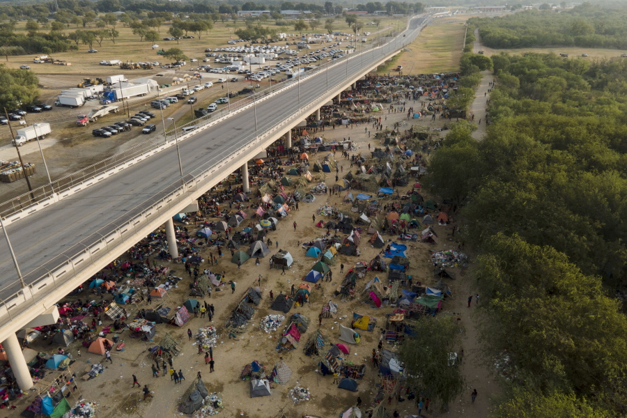 Migrants, many from Haiti, are seen at an encampment along the Del Rio International Bridge near the Rio Grande, Tuesday, Sept. 21, 2021, in Del Rio, Texas.  The options remaining for thousands of Haitian migrants straddling the Mexico-Texas border are narrowing as the United States government ramps up to an expected six expulsion flights to Haiti and Mexico began busing some away from the border.