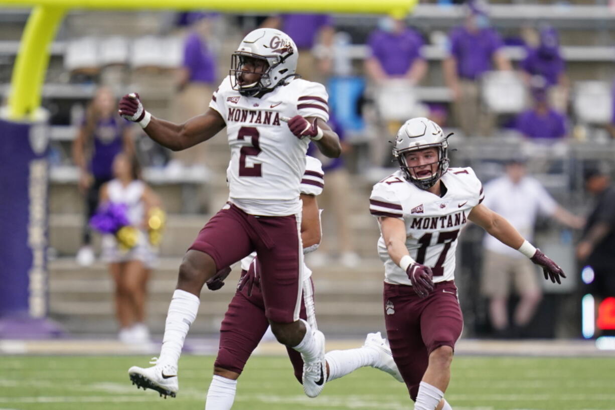 Montana's Gavin Robertson (2) leaps in celebration after making an interception against Washington as teammate Robby Hauck follows in the first half of an NCAA college football game Saturday, Sept. 4, 2021, in Seattle.