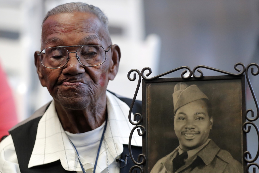 World War II veteran Lawrence Brooks holds a photo of him taken in 1943, as he celebrates his 110th birthday Sept. 12, 2019. Brooks celebrated his 112th birthday Sunday with a drive-by party at his New Orleans home.