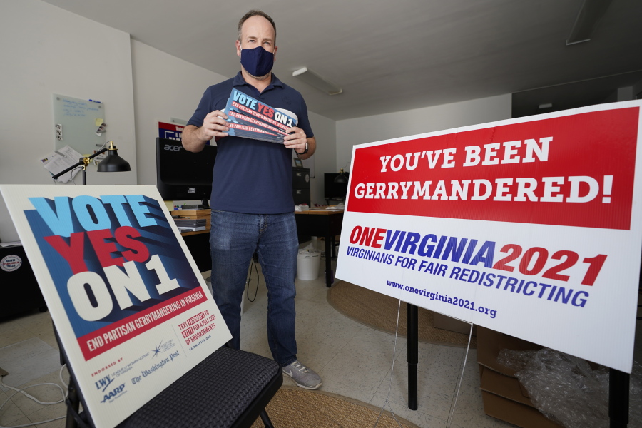 FILE - In this Oct. 6, 2020 file photo, redistricting reform advocate Brian Cannon poses with some of his yard signs and bumper stickers in his office in Richmond, Va.  A new voter-approved commission in Ohio that was supposed to reduce partisanship in the once-a-decade process of political map-drawing has already become a flop.  Similar commissions meeting for the first time in New York and Virginia have devolved into partisan finger-pointing, undermining their intent.