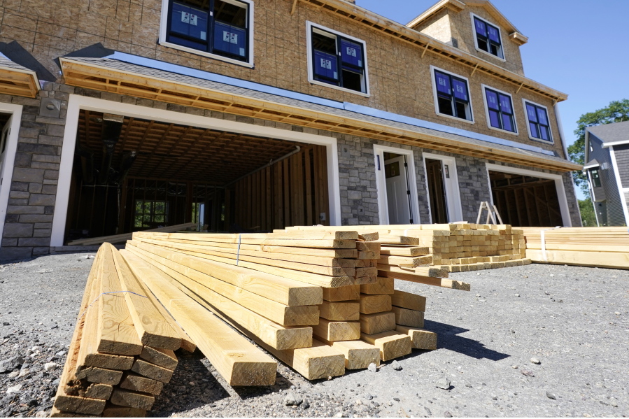 In this June 24, 2021 photo, lumber is piled at a housing construction site in Middleton, Mass.  Rising costs and shortages of building materials and labor are rippling across the homebuilding industry, which accounted for nearly 12% of all U.S. home sales in July. Construction delays are common, prompting many builders to pump the brakes on the number of new homes they put up for sale. As building a new home gets more expensive, some of those costs are passed along to buyers.