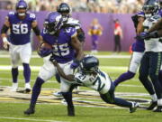 Minnesota Vikings running back Alexander Mattison (25) is tackled by Seattle Seahawks cornerback Tre Flowers (21) in the first half of an NFL football game in Minneapolis, Sunday, Sept. 26, 2021.