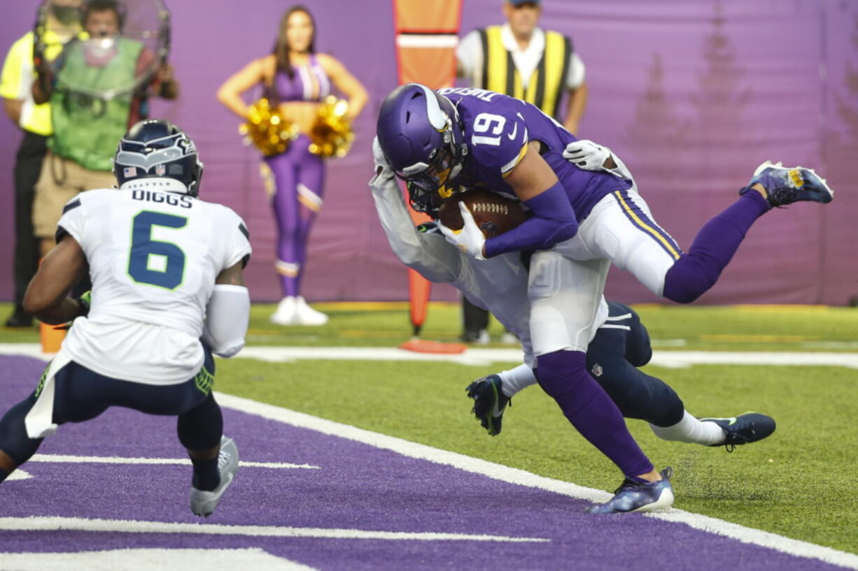 Minnesota Vikings wide receiver Adam Thielen (19) scores a touchdown on a catch in front of Seattle Seahawks strong safety Quandre Diggs (6) in the first half of an NFL football game in Minneapolis, Sunday, Sept. 26, 2021.