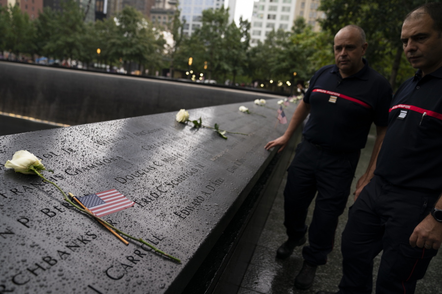 Visitors browse the south pool as flowers and American flags rest among the names of the fallen at the National September 11 Memorial & Museum, Thursday, Sept. 9, 2021, in New York.