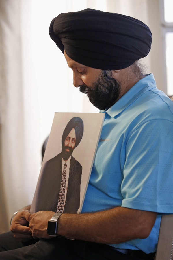 FILE - In this Aug. 19, 2016 file photo Rana Singh Sodhi, holds a photograph of his murdered brother, Balbir Singh Sodhi, in Gilbert, Ariz. The Sikh American was killed at his Arizona gas station four days following the Sept. 11 attacks by a man who announced he was "going to go out and shoot some towel-heads" and mistook him for an Arab Muslim. (AP Photo/Ross D.