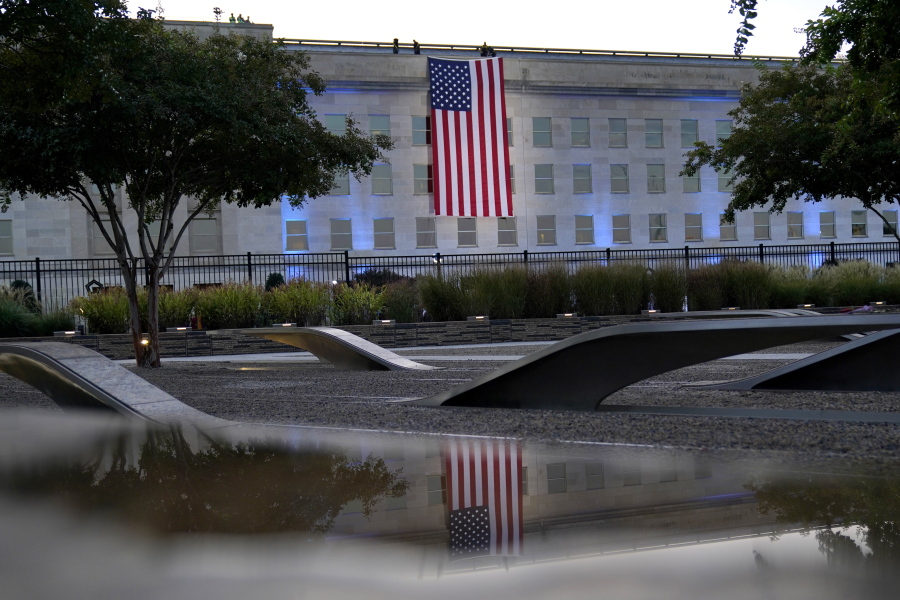 An American flag is unfurled at the Pentagon in Washington, Saturday, Sept. 11, 2021, at sunrise on the morning of the 20th anniversary of the terrorist attacks. The American flag is draped over the site of impact at the Pentagon. In the foreground, the National 9/11 Pentagon Memorial, opened in 2008 adjacent to the site, commemorates the lives lost at the Pentagon and onboard American Airlines Flight 77.